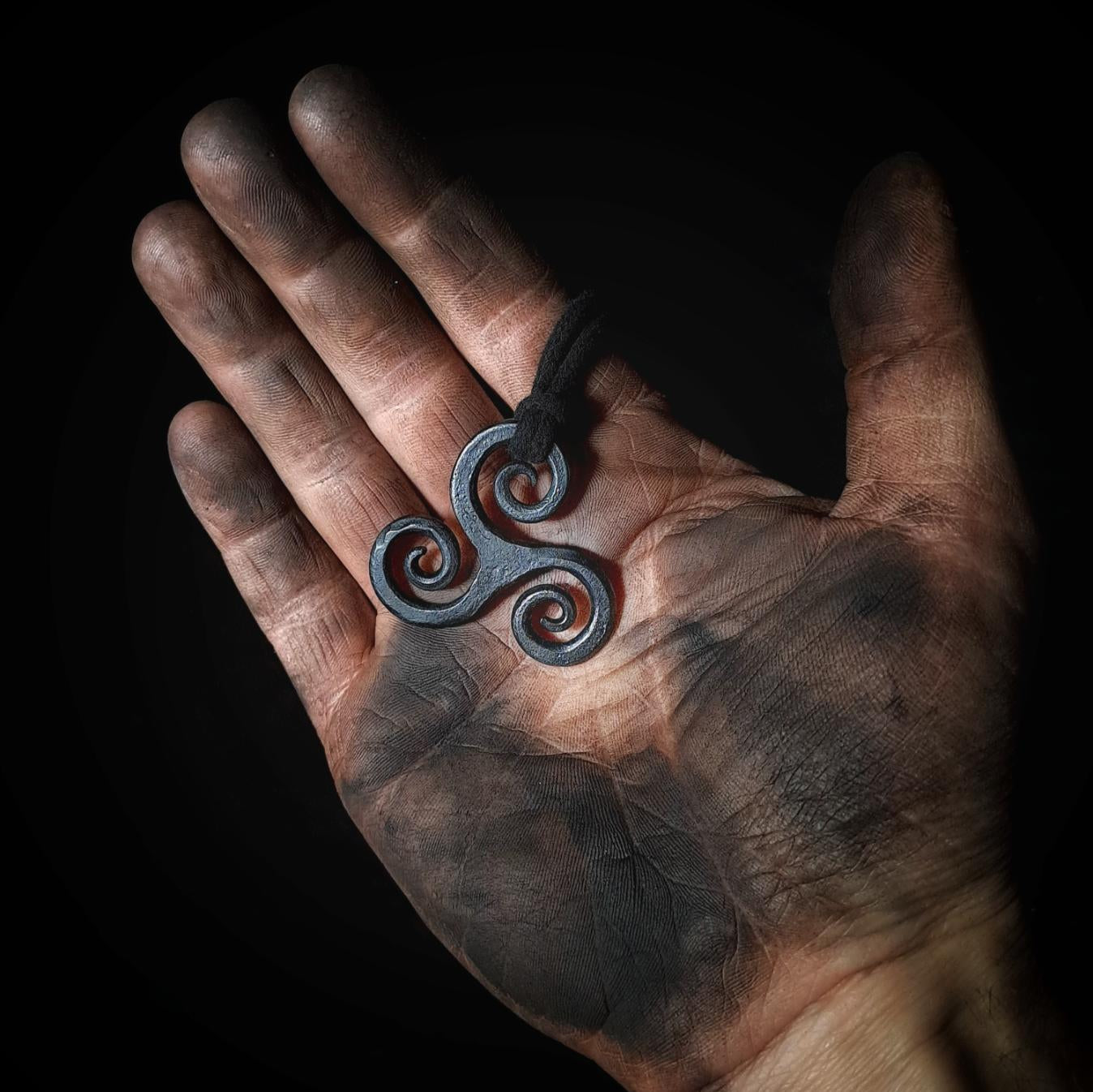 holding a triskele pendant