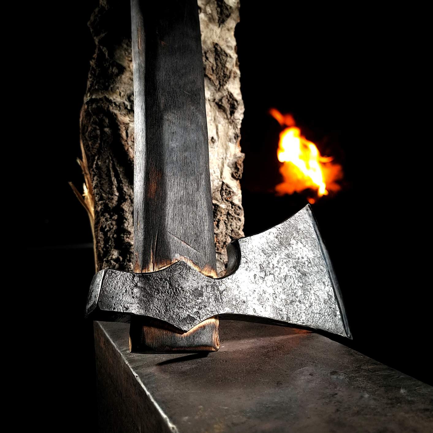 A close-up photo of a hand-forged authentic Viking axe in a.  The axe head is forged from high-carbon steel and the handle is made from carefully selected hardwood.