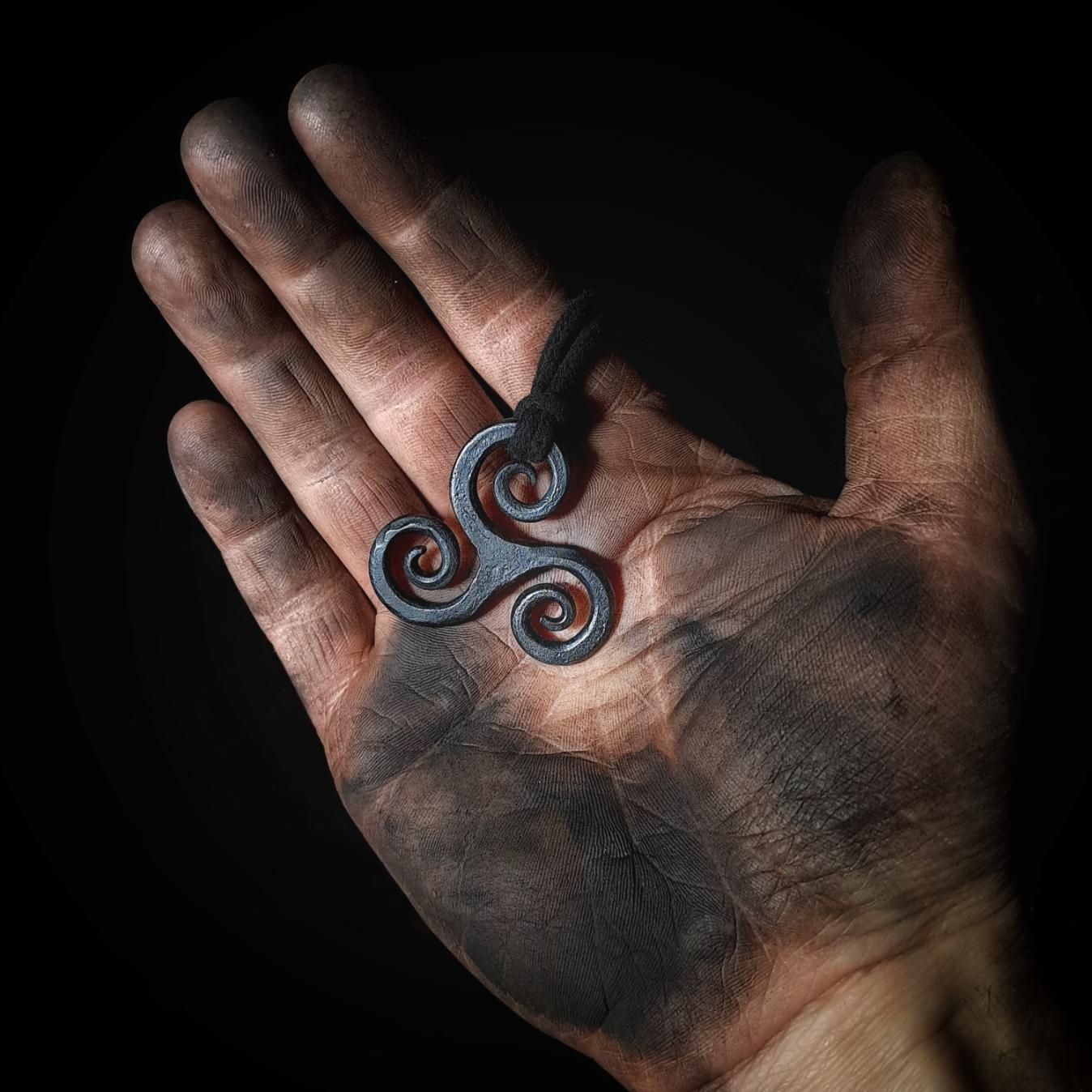 holding a triskele pendant