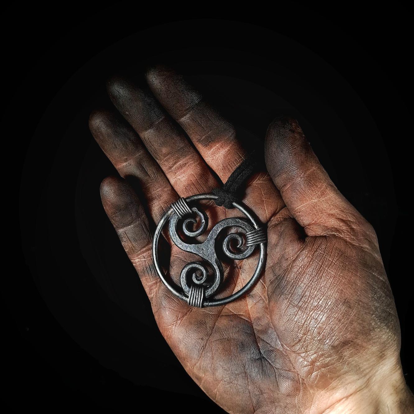 holding a triskele pendant in hands