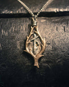 Ancient-inspired bronze pendant showcasing delicate bindrune markings within an organic leaf-like frame