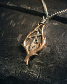 Detailed bronze amulet with intertwined runic symbols, photographed with shallow depth of field highlighting the metalwork